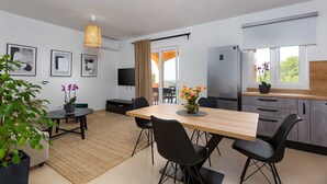 A modern kitchen with a dining area, a TV, and a large window with a view.