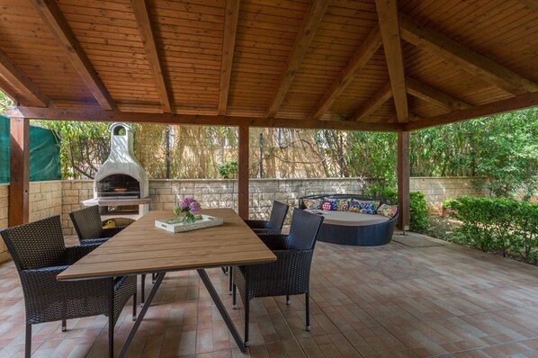 Relax in a cozy outdoor space with a fireplace, comfortable seating, and lush greenery.