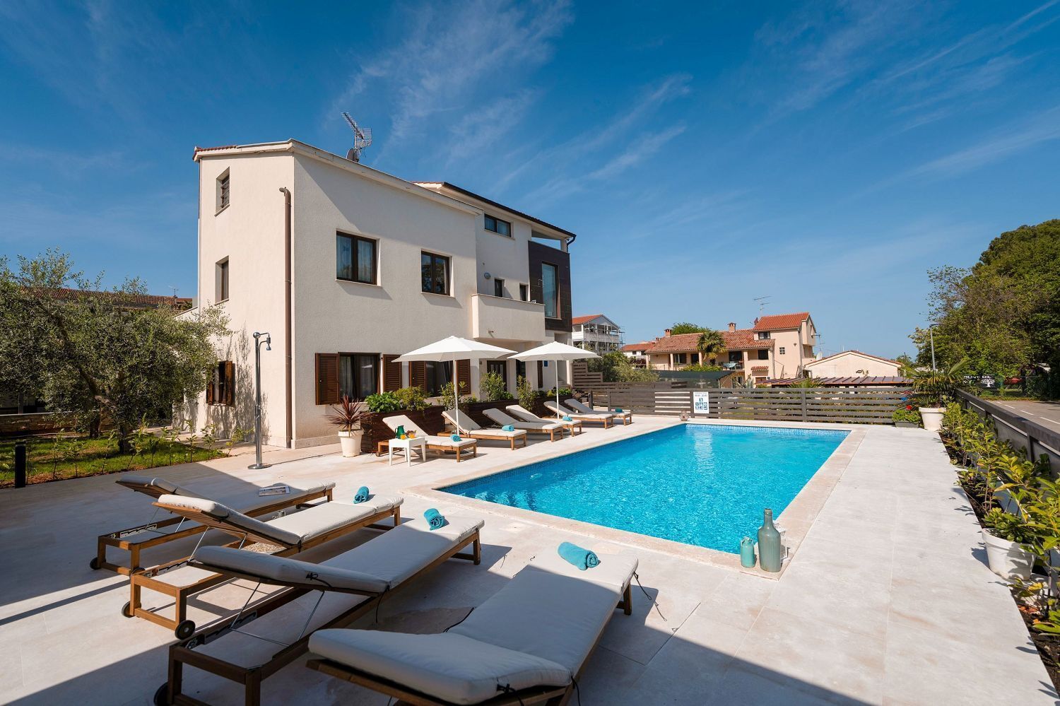 Ein modernes Gebäude mit Swimmingpool, Liegestühlen und Sonnenschirmen.