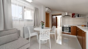 A modern kitchen with white cabinetry, a built-in oven, and a dining area with a round table and white chairs. - Fantastic flat only 100 metres to the beach with jacuzzi, sea view, saltwater pool (Funtana)