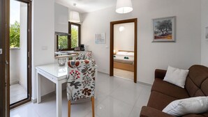 Un salon moderne avec un canapé, un coin repas comprenant une table et des chaises, et une chambre à coucher avec un lit.
