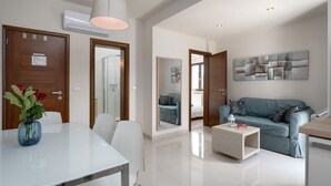 A modern living room with a sofa, coffee table, and a dining area with a table and chairs. - Mediterranean flat with saltwater pool, jacuzzi and only 100 metres to the beach (Funtana)