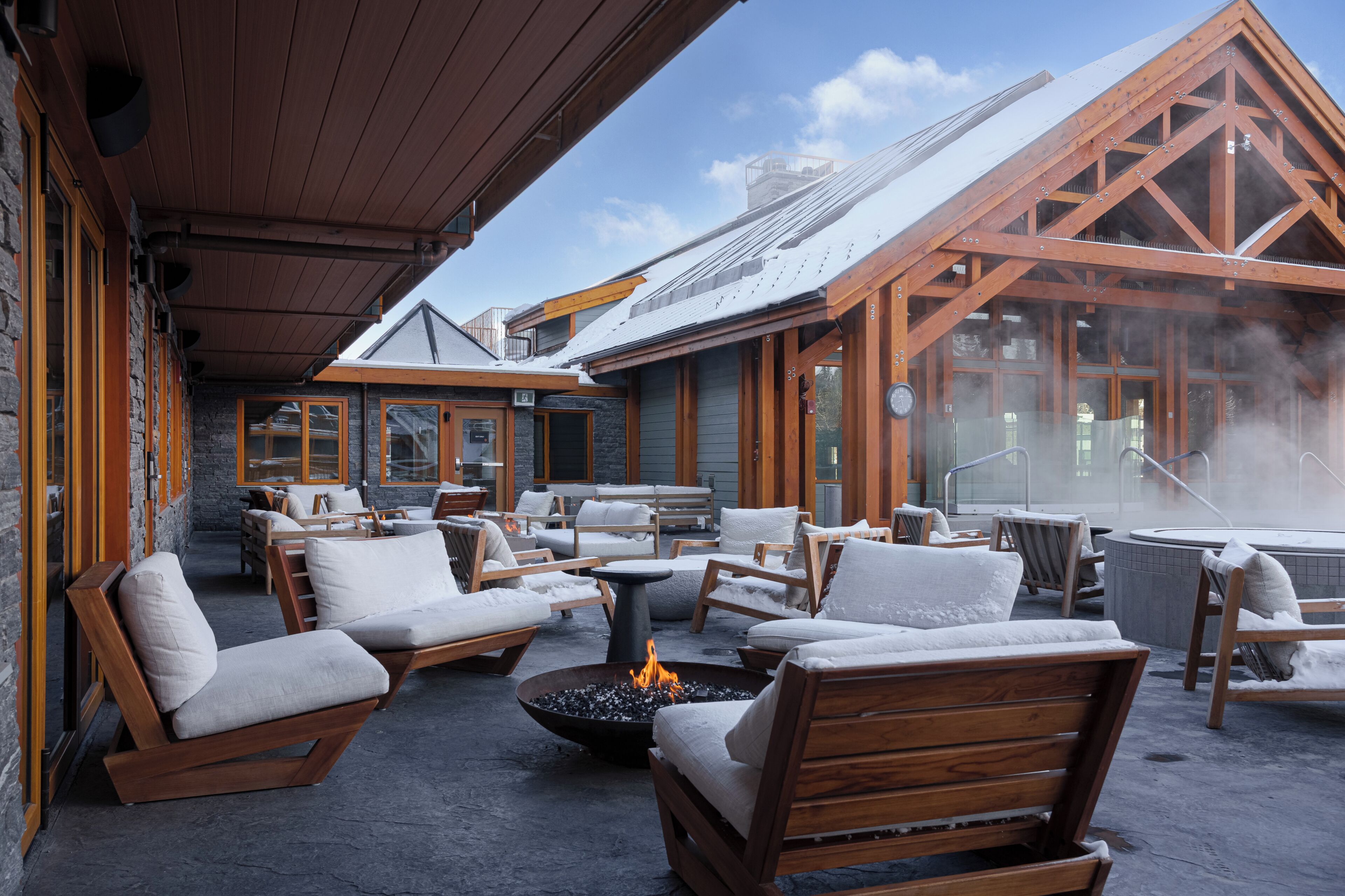 A covered outdoor seating area with wooden furniture and a fire pit.