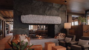 A cozy lounge area with a stone fireplace, leather seating, and a wooden coffee table. - Otter Hotel (Banff)