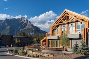 A modern building with large windows and a wooden facade, set against a mountain backdrop. - Otter Hotel (Banff)
