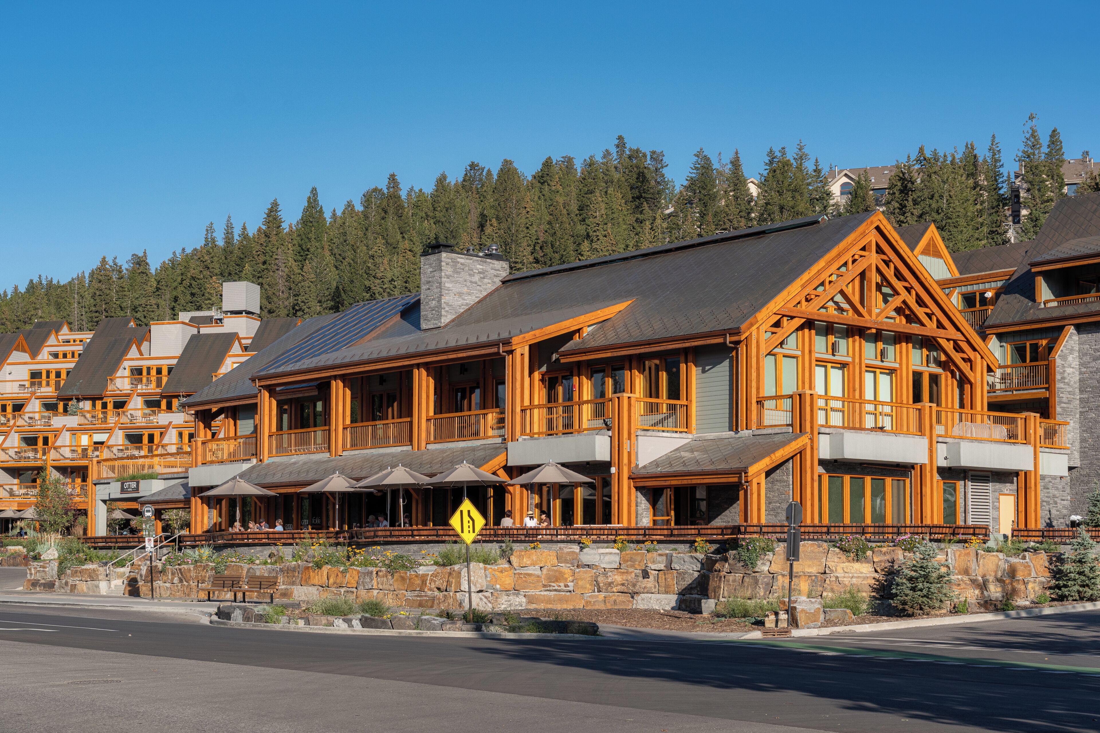 A lodge with multiple guest rooms, outdoor seating, and a stone retaining wall.