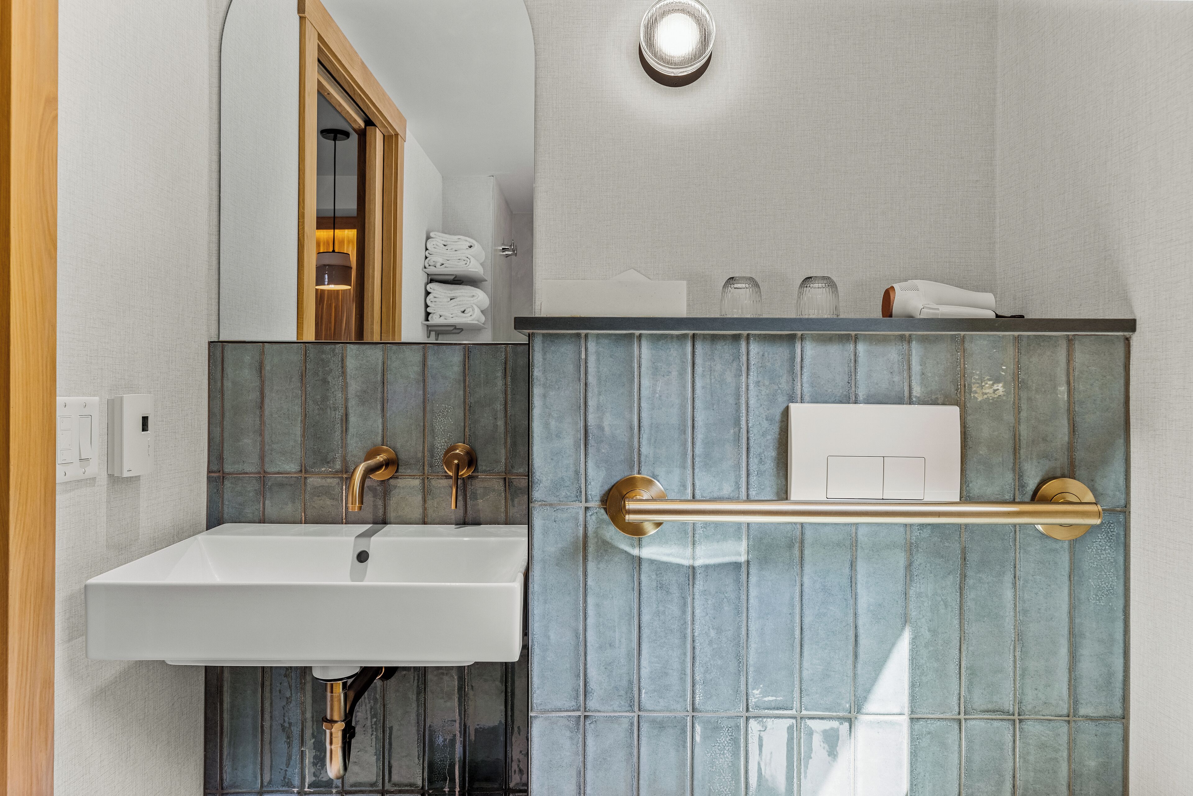 A modern bathroom with a white sink, a towel rack, and a mirror.
