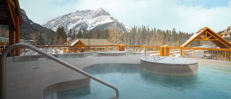 A hot tub area with a view of snow-capped mountains and a wooden deck.