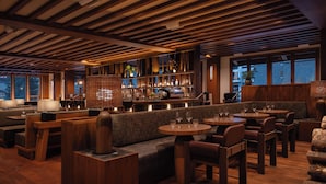 A modern restaurant with wooden flooring, cushioned seating, and a bar area. - Otter Hotel (Banff)