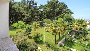 A balcony with a view of a well-maintained garden featuring various trees and shrubs. - Charming flat just 350 metres from the beach with private balcony and sea view (Porec)