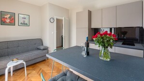 A modern kitchen with a central island, a grey sofa, and a dining area. - Idyllic flat just a few minutes' walk from the beach with private balcony, air conditioning, barbecue, WiFi (Porec)