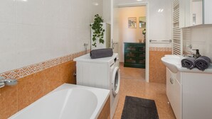 A modern bathroom with a bathtub, a washing machine, a sink, and a green cabinet. - Idyllic flat just a few minutes' walk from the beach with private balcony, air conditioning, barbecue, WiFi (Porec)