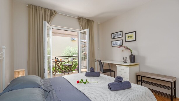 A bedroom with a bed, a desk, a chair, a bench, and a balcony with a table and chairs. - Idyllic flat just a few minutes' walk from the beach with private balcony, air conditioning, barbecue, WiFi (Porec)