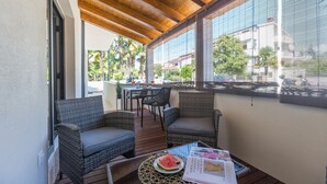 A covered outdoor seating area with wicker furniture and a table with a watermelon slice and magazines.