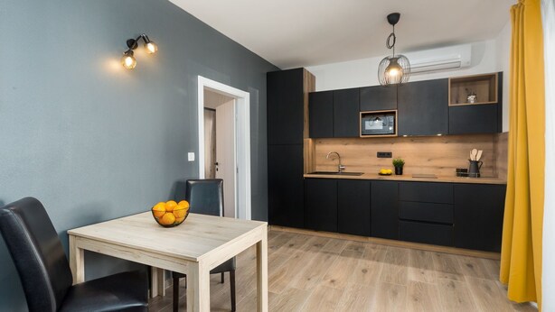 A modern kitchen with dark cabinets, a wooden countertop, and a built-in microwave.