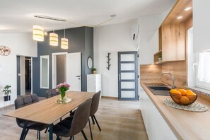 A modern kitchen with a wooden countertop, a sink, and a bowl of oranges. There is a dining area with a wooden table and chairs, and a vase of flowers. - Extravagant flat just 250 metres from the beach with private balcony, barbecue, WiFi (Porec)