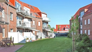 Ein Wohngebäude mit mehreren Balkonen, einem gepflegten Rasen und einer Ziegel-Fassade.