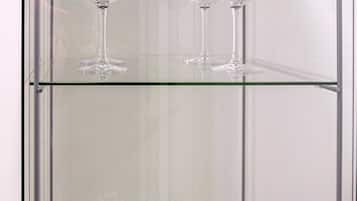 A glass display case with two wine glasses on the top shelf and two keychains on the bottom shelf.