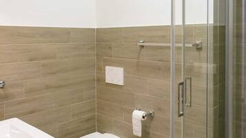Un baño moderno con cabina de ducha de vidrio, inodoro, bidé y lavabo.