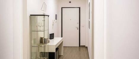 A modern bathroom with a glass shower enclosure, a white sink, and a wooden floor.
