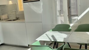 A modern kitchen with a built-in oven and a dining area with green chairs and a white table. - Historic center, lovely air-conditioned apartment with terrace.  (AIX EN PROVENCE)