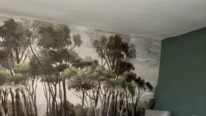 A living room with a mural of trees on the wall, grey sofas, and wooden flooring. - Historic center, lovely air-conditioned apartment with terrace.  (AIX EN PROVENCE)