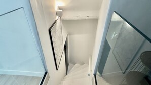 A staircase with a glass railing, white walls, and a framed picture on the wall. - Historic center, lovely air-conditioned apartment with terrace.  (AIX EN PROVENCE)