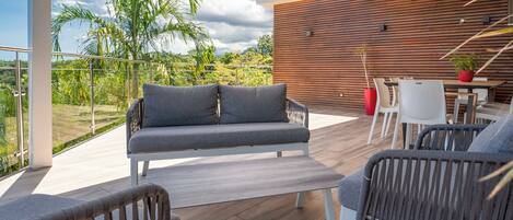 A modern outdoor patio with a sofa, chairs, and a dining table.