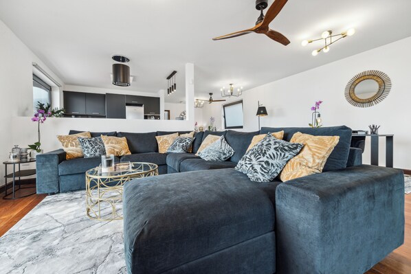 A modern living room with a sectional sofa, a coffee table, and a dining area.
