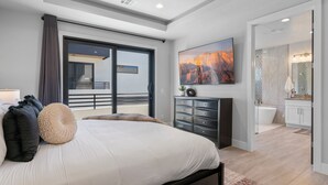 A modern bedroom with a large bed, a dresser, and a painting on the wall.