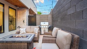 An outdoor patio with wicker furniture, a fire pit, and a grill.