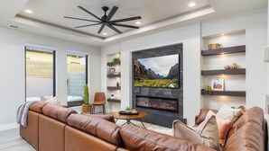 A modern living room with a leather sofa, a fireplace, and a large TV screen.
