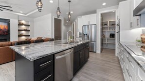A modern kitchen with granite countertops, stainless steel appliances, and pendant lighting.