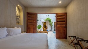 A bedroom with a large bed, wooden shutters, and a view of an outdoor pool area. - Casa Fernández Cartagena (Cartagena)