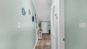 A hallway with light green walls, a wooden floor, and a white door at the end. - Okaloosa Island Castaway-Pets Allowed (Fort Walton Beach)