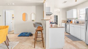 Een moderne keuken met witte kasten, een centraal eiland en een barstoel.