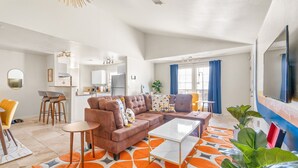 Een moderne woonkamer met een modulaire bank, een salontafel en een eethoek met barstoelen.