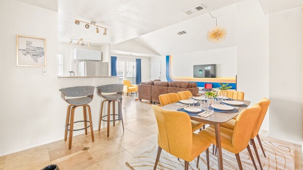Een moderne woonkamer met een eetgedeelte, keuken en een bank.