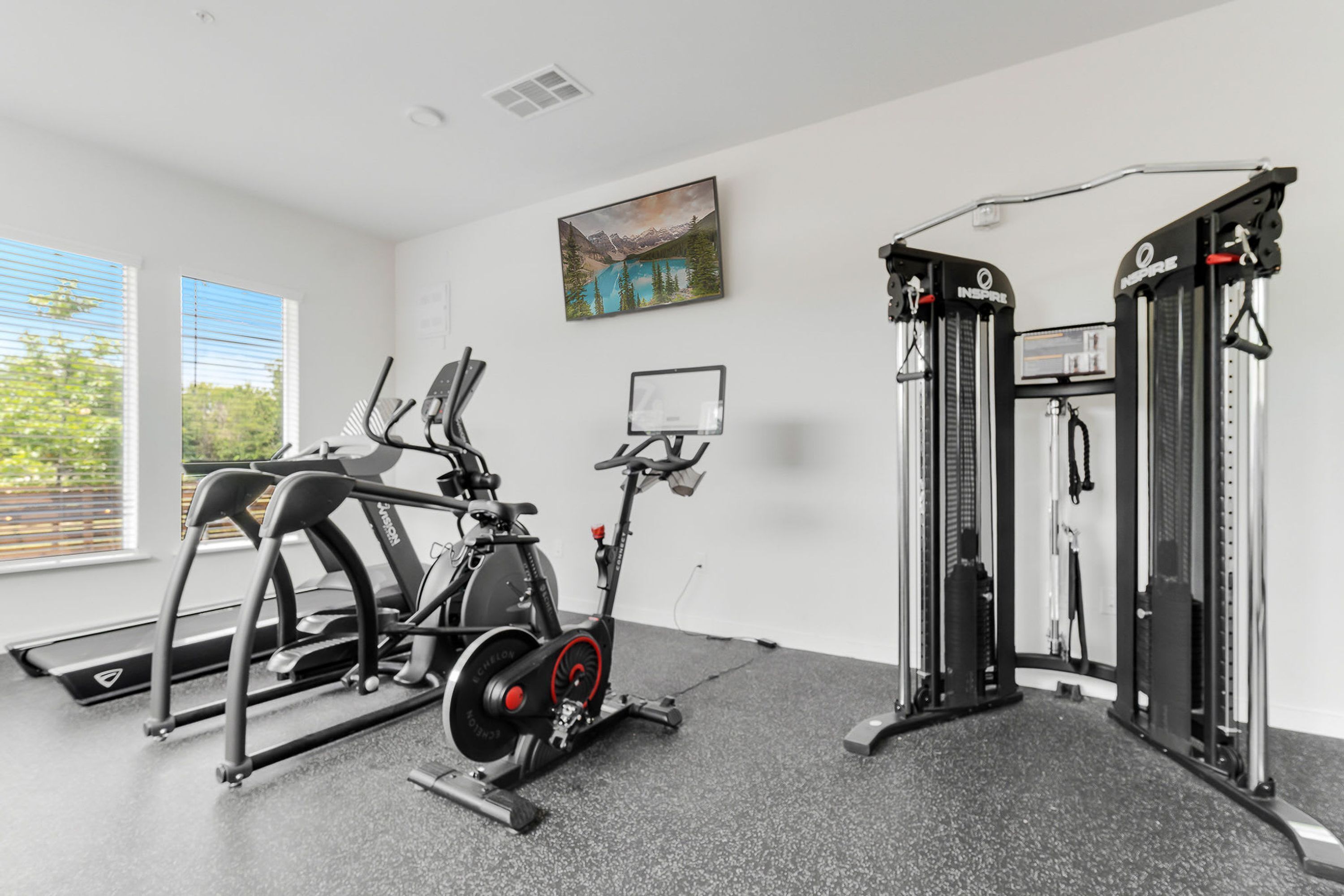A gym with cardio equipment, weight machines, and a painting of a mountain landscape.
