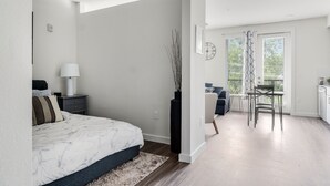 A modern bedroom with a bed, bedside table, lamp, and a tall vase. - Downtown Modern Bungalow (Dallas)