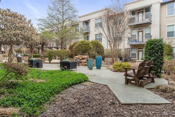 A courtyard with a fire pit, seating area, and a small tree. - Kaleidoscope Near Galleria Medical City (Dallas)