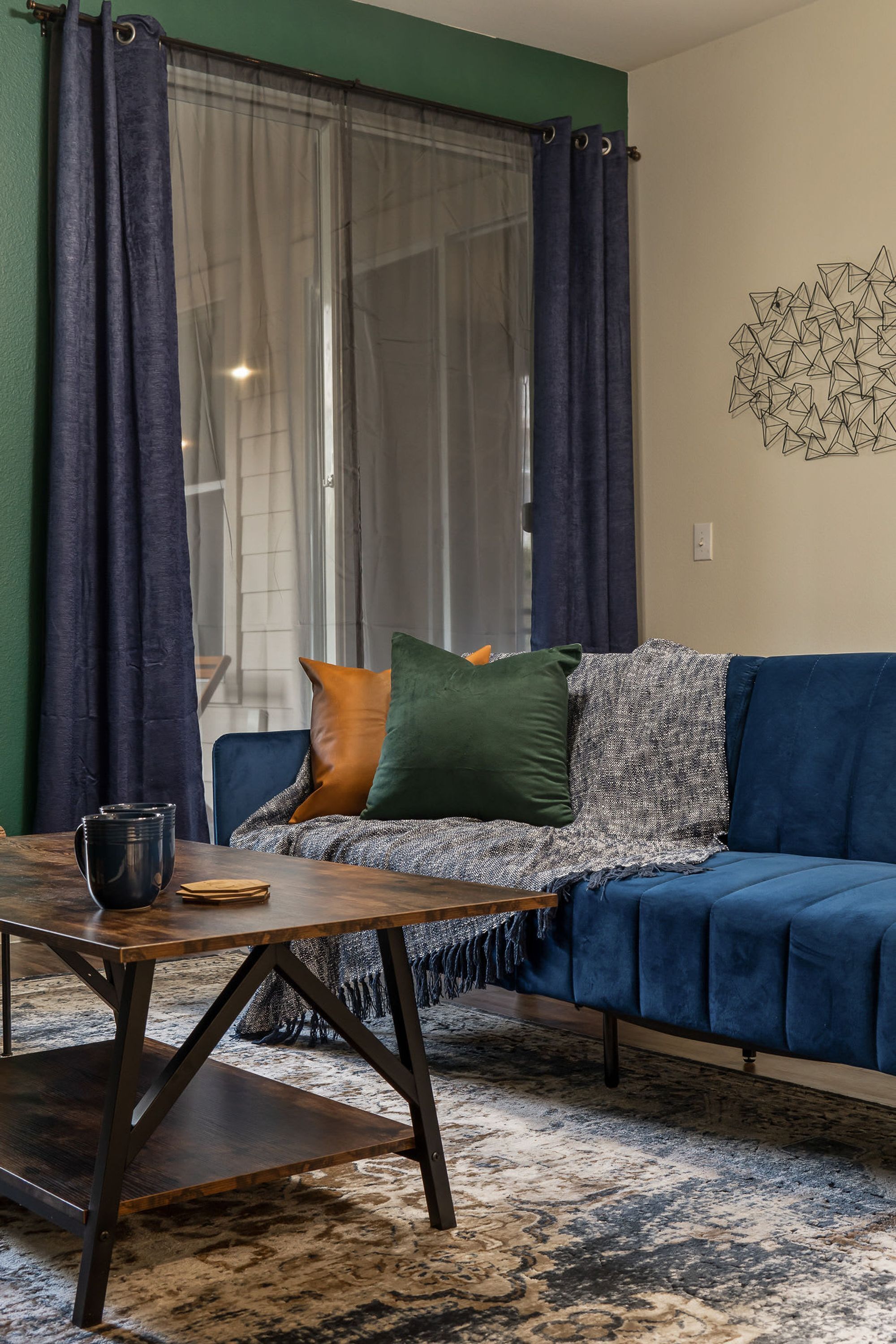 A cozy living room with a blue sofa, a wooden coffee table, and a patterned rug.