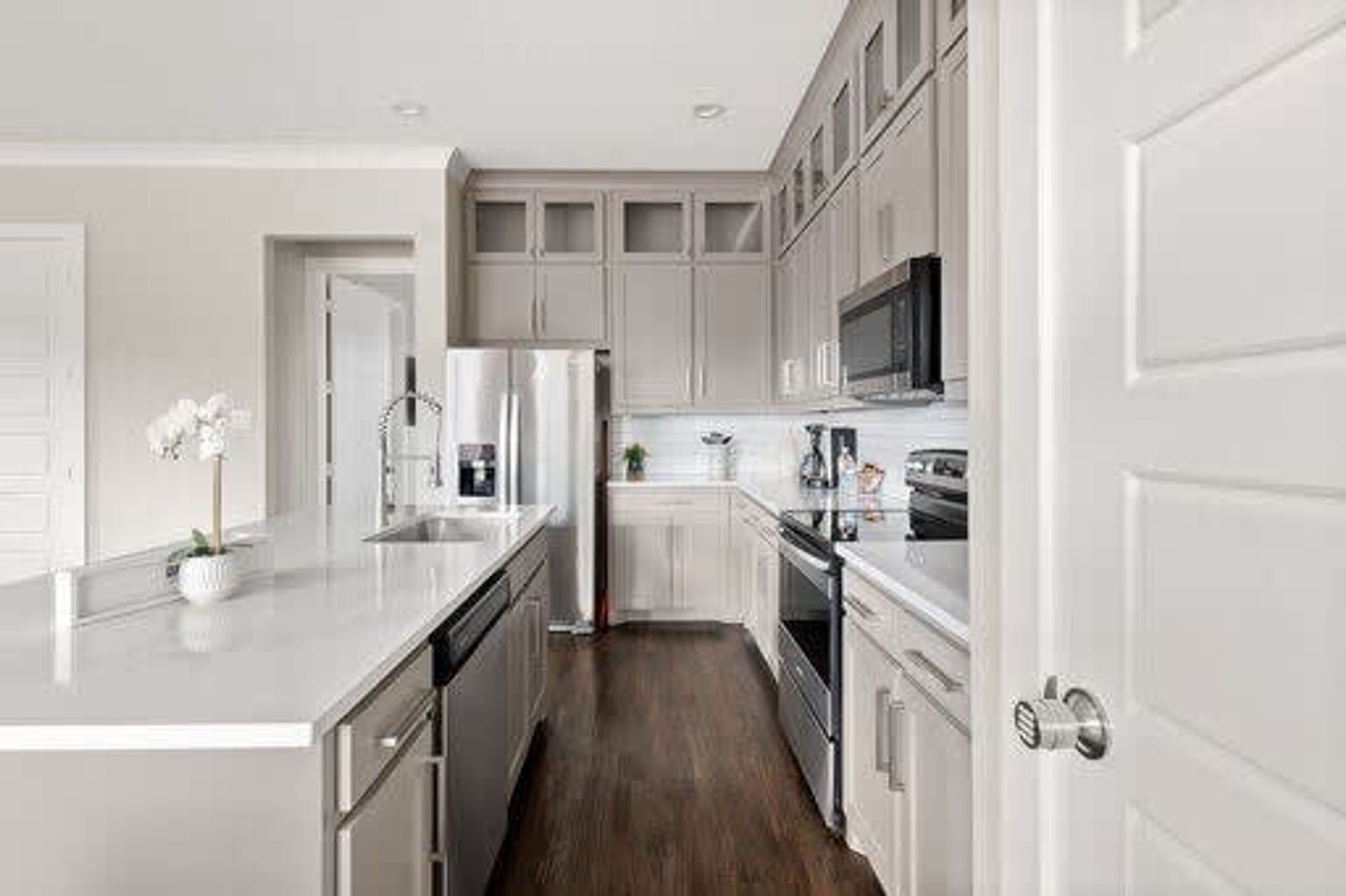 A modern kitchen with white cabinetry, stainless steel appliances, and a central island.