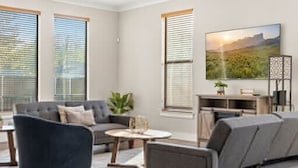A modern living room with a sofa set, a coffee table, and a TV on a stand. - Trinity Groves Retreat Large Modern 5 BR Home (Dallas)