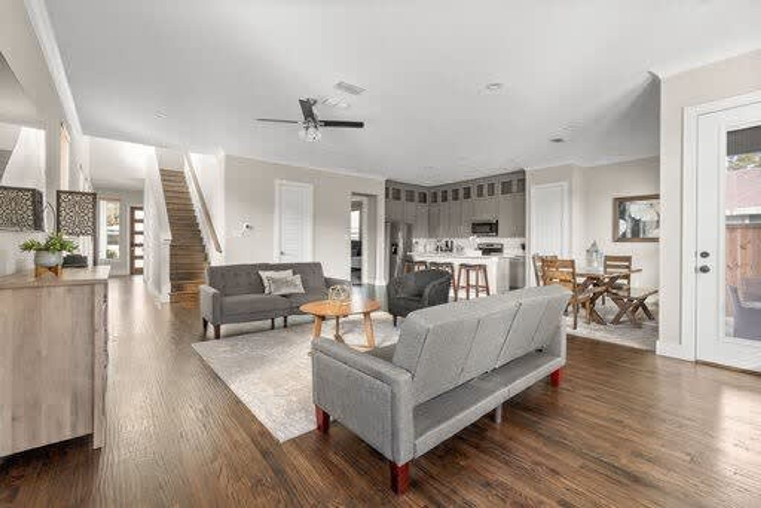 Un salon moderne avec un canapé gris, une table basse et un escalier menant à un niveau supérieur.