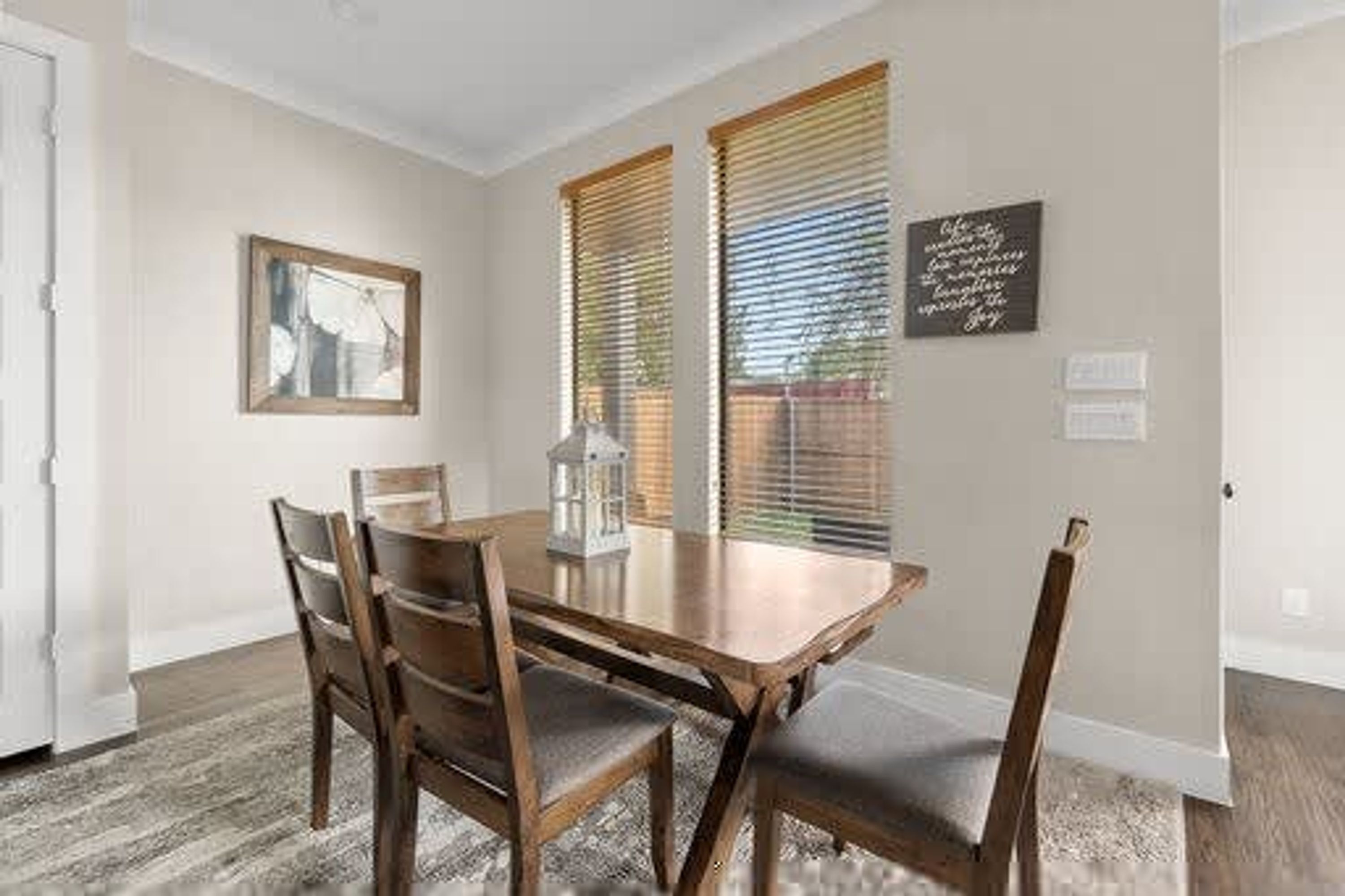Un comedor con mesa y sillas de madera, un cuadro enmarcado en la pared y una ventana con persianas.