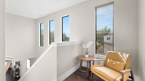 A modern interior with a staircase, a yellow chair, and a small table with a plant. - Trinity Groves Retreat Large Modern 5 BR Home (Dallas)