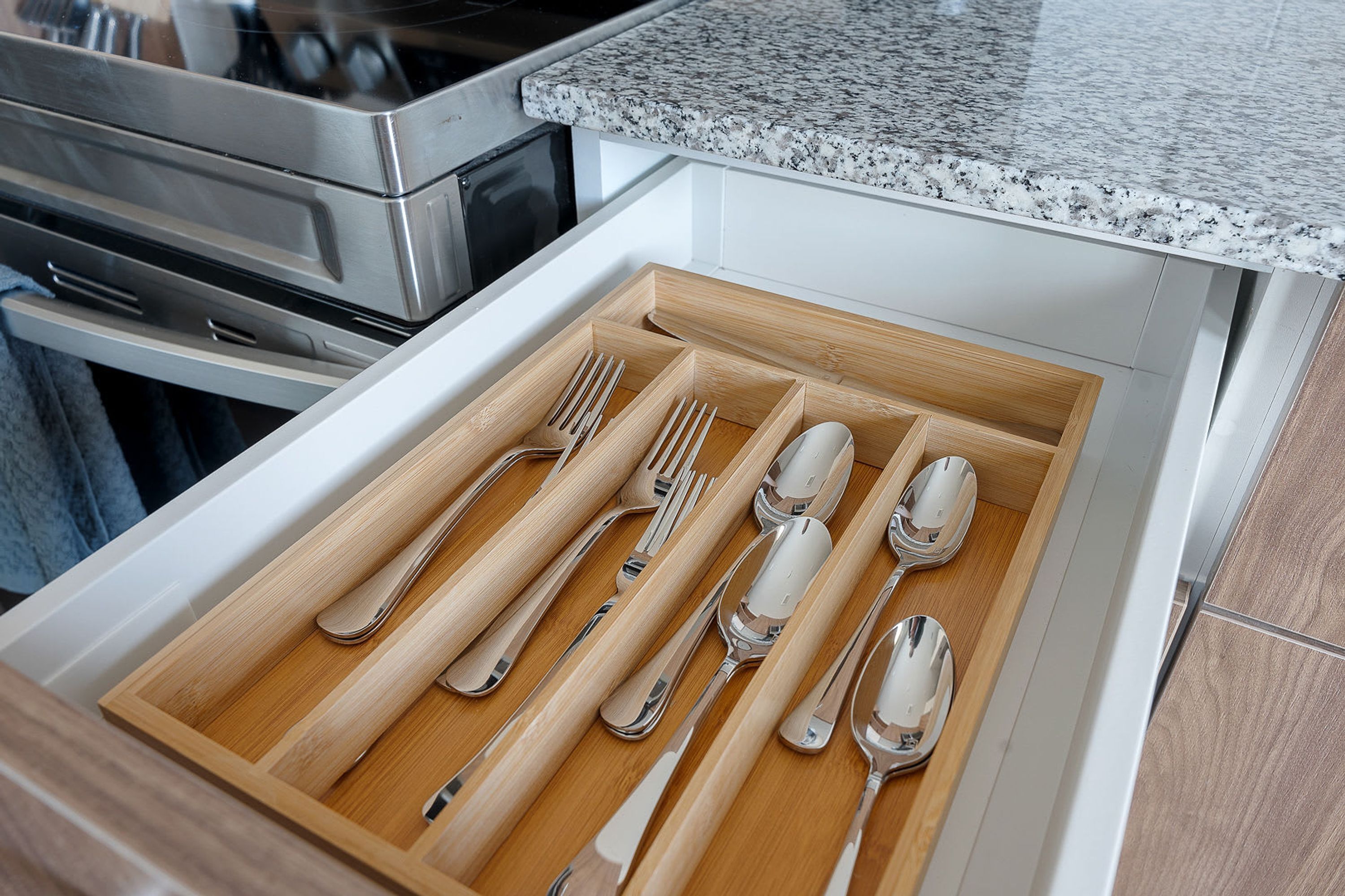 A drawer with neatly arranged silverware and wooden handles.