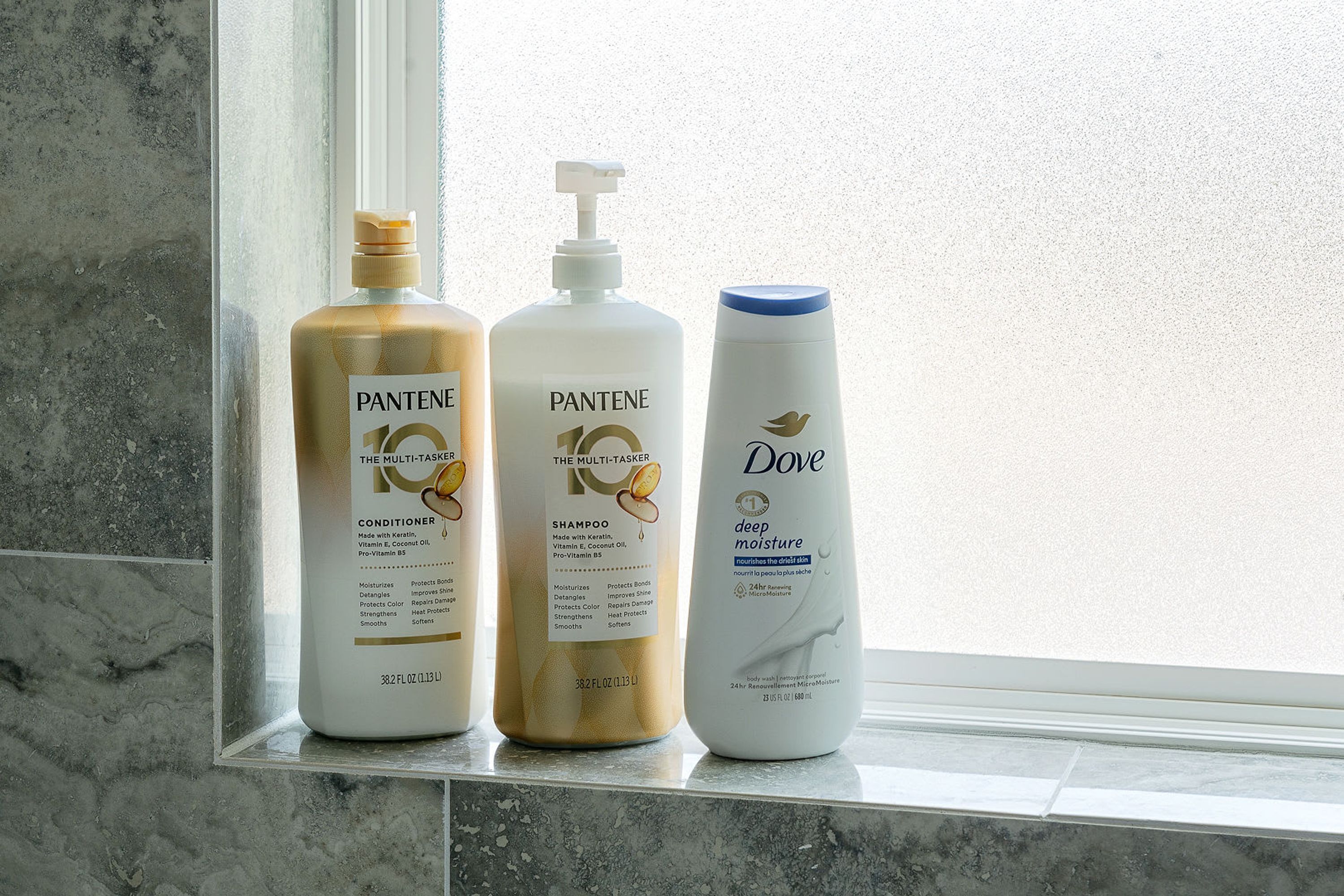 Tres productos Pantene sobre una encimera de baño junto a una ventana.