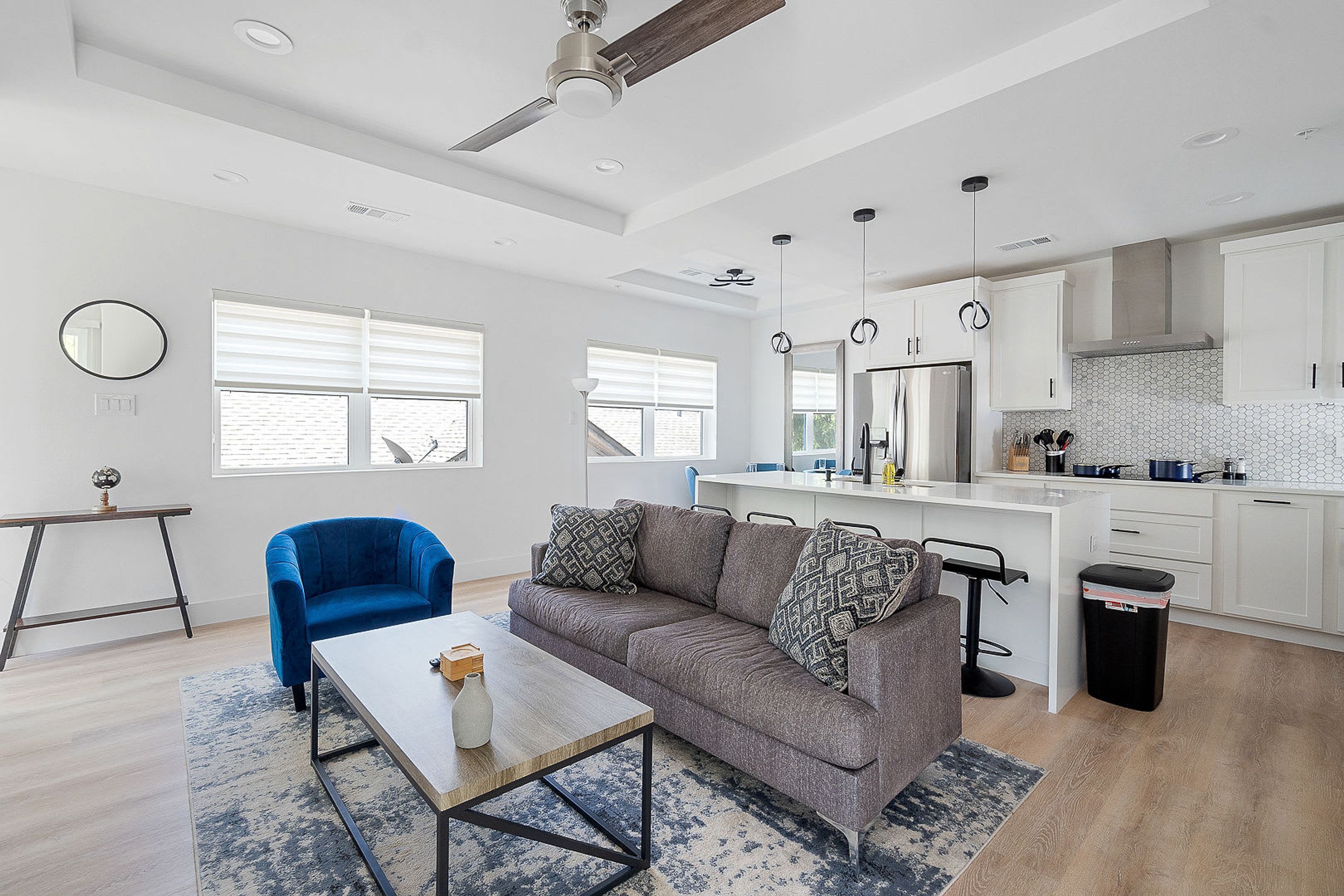 Una sala de estar moderna con un sofá gris, un sillón azul y una mesa de centro de madera.